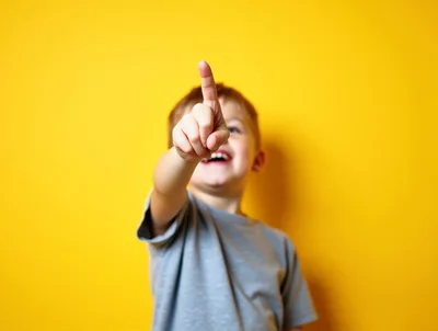 Happy Young Boy Pointing Finger At Camera