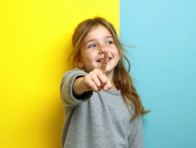 Young Girl Pointing Forward Against Colorful Background