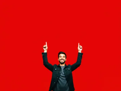 Happy Man Pointing Upwards Against Red Background