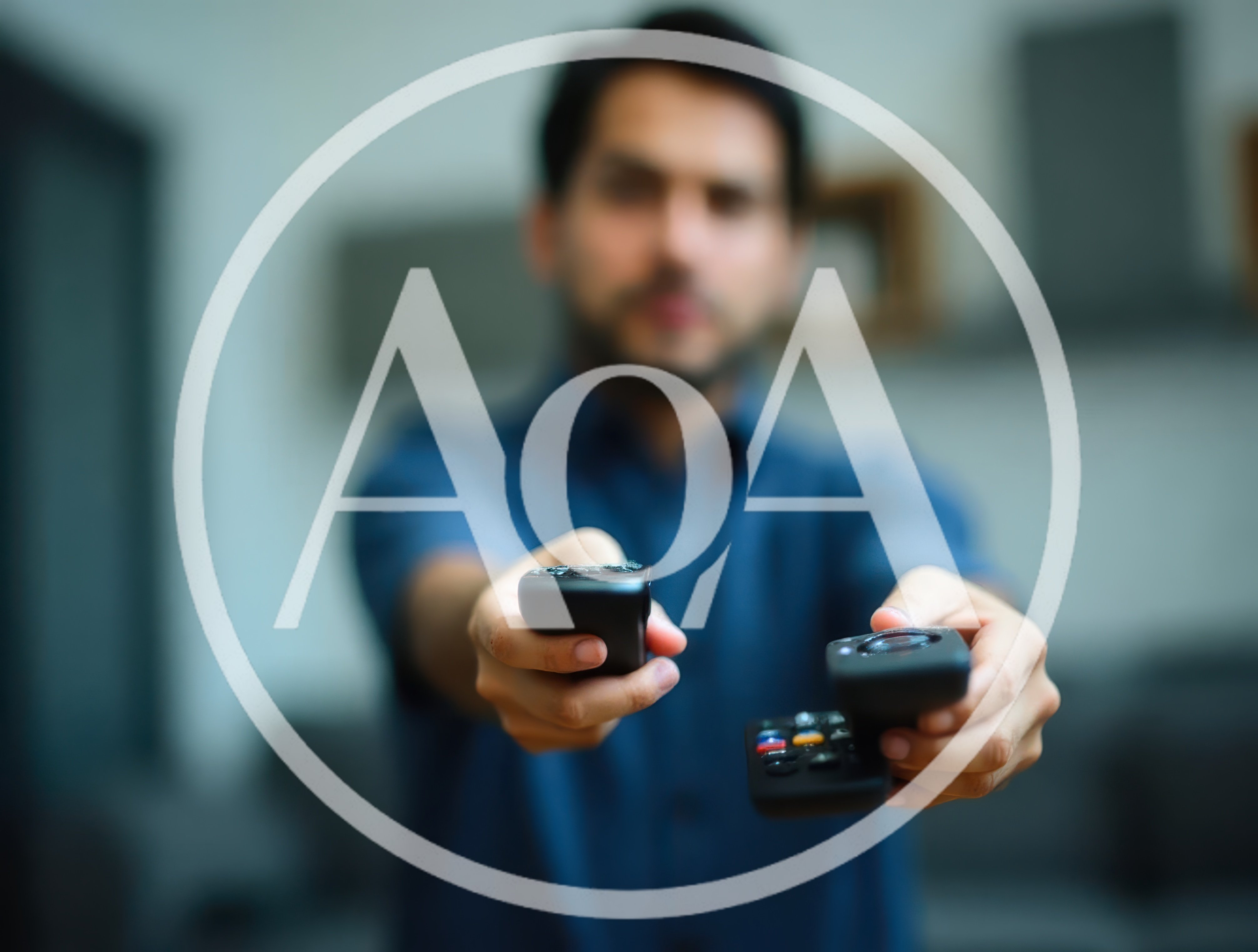 Man Holding Two Remote Controls Towards Camera
