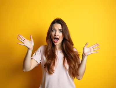 Surprised Young Woman With Mouth Open Against Yellow Background