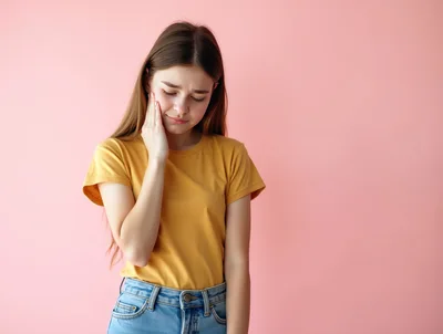 Young Woman Suffering From Toothache Against Pink Background