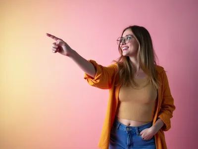 Young Woman Pointing To The Side Against Pink Background
