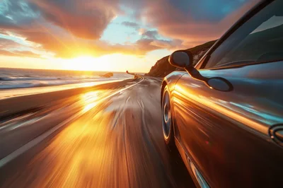 Sports Car Driving Along Coastal Highway At Sunset