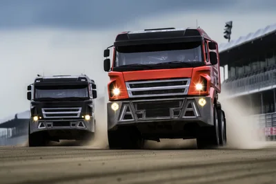 Two Racing Trucks Competing On A Dusty Track