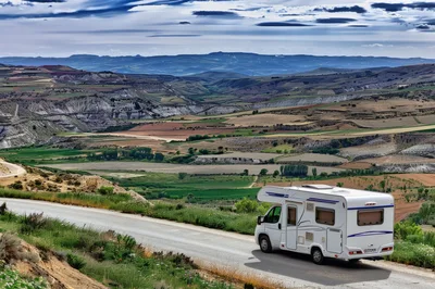 White Camper Van Driving Along A Scenic Mountain Road