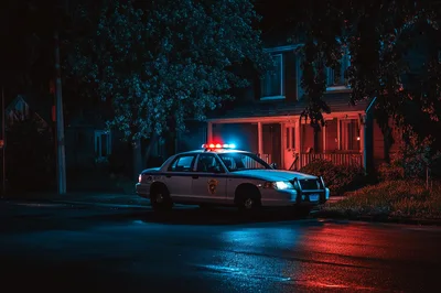 Police Cruiser Parked Outside Residential House At Night