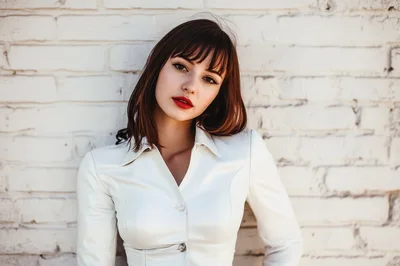 Portrait Of A Young Woman With Bangs Against Brick Wall