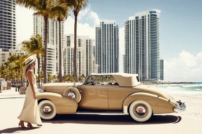 Elegant Woman Standing Beside Vintage Convertible On Beach