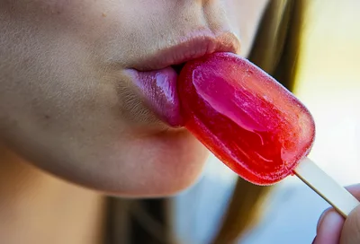 Close Up Of A Woman Eating A Red Popsicle