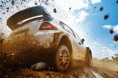 Rally Car Drifting Through Muddy Terrain
