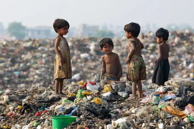 Children Standing Amidst A Large Garbage Landfill