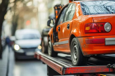 Orange Car Being Transported On A Flatbed Tow Truck