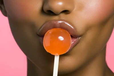 Close Up Of Woman Holding Orange Lollipop