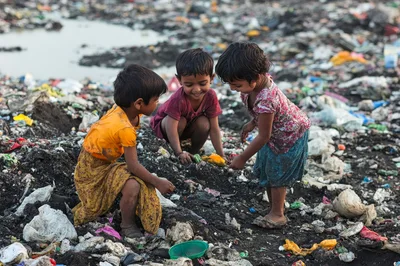 Three Children Playing Amidst Trash in a Landfill