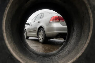 Silver Sedan Seen Through A Large Tire