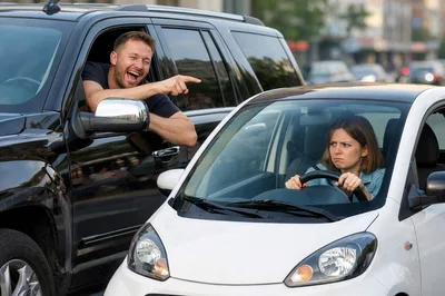 Man Laughing And Pointing At Woman Driving Small Car