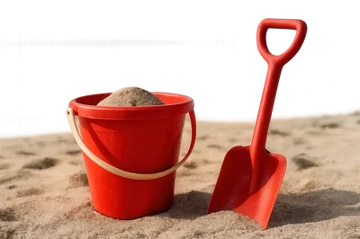 Red Plastic Beach Bucket And Shovel In Sand