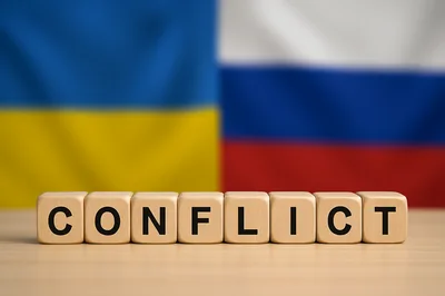 Wooden Blocks Spelling Conflict Against Ukrainian and Russian Flags
