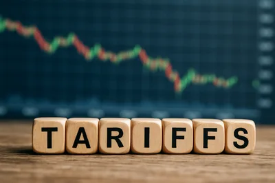 Wooden Blocks Spelling Tariffs Against A Stock Market Chart