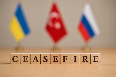 Wooden Blocks Spelling Ceasefire With Blurred National Flags