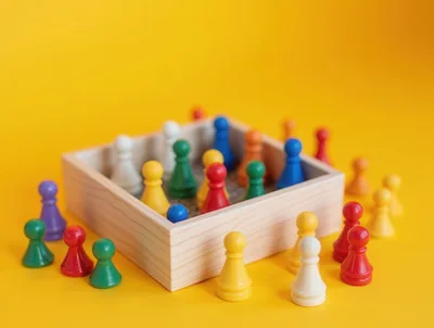 Colorful Board Game Pawns Scattered Around Wooden Box