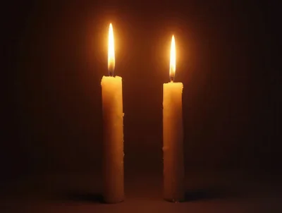 Two Lit Candles Burning In The Dark