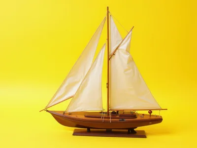 Wooden Model Sailboat Against A Bright Yellow Background