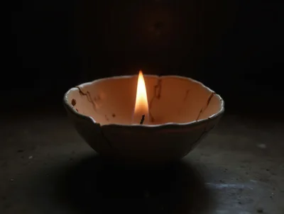 Lit Candle Inside A Cracked Ceramic Bowl