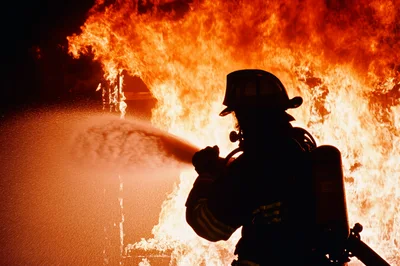 Firefighter Silhouetted Against Intense Building Fire