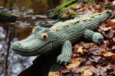Crocheted Toy Alligator Resting Near A Forest Stream