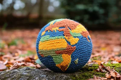 Crocheted Globe Resting On Mossy Forest Ground
