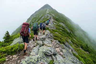 Group Of Hikers Trekking Up A Steep Mountain Ridge