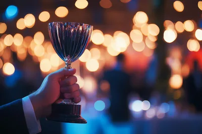 Hand Holding A Shiny Silver Trophy At An Event