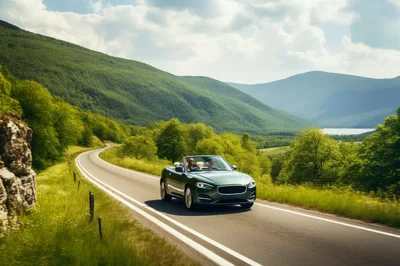 Green Convertible Driving Along A Scenic Mountain Road