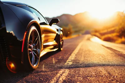 Black Sports Car Parked On Desert Road At Sunset