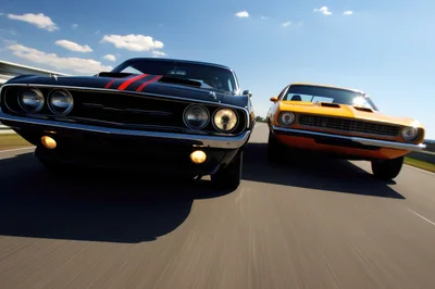 Two Classic Muscle Cars Racing On A Highway
