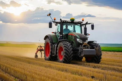 Green Tractor Cultivating Field During Golden Hour