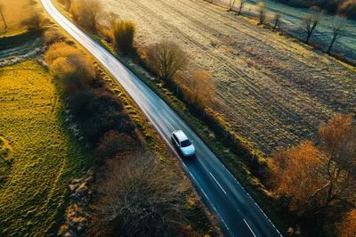 Aerial View Of A Silver Car Driving On Country Road