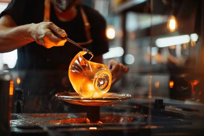 Glassblower Shaping Molten Glass In A Workshop