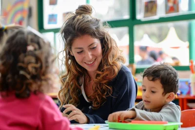 Preschool Teacher Helping Children With Classroom Activities