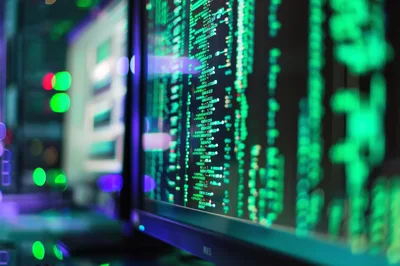 Computer Monitor Displaying Green Programming Code In Server Room