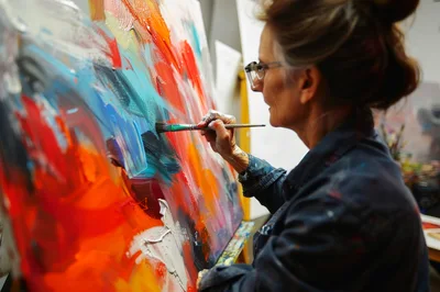 Mature Female Artist Painting Abstract Art In Studio