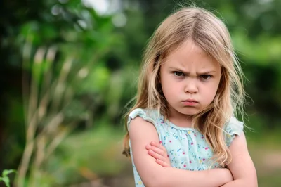 Angry Little Girl With Crossed Arms Outdoors
