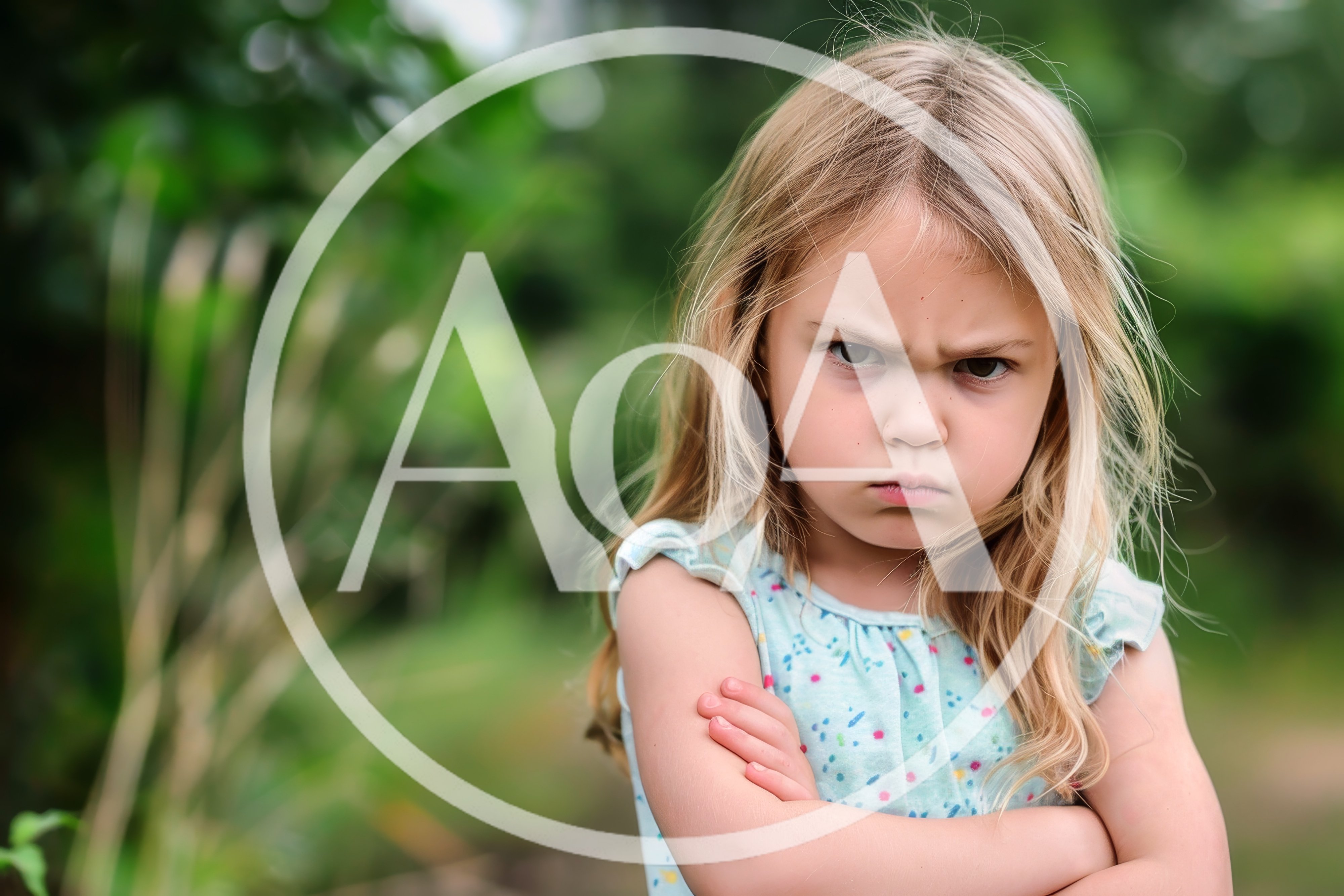 Angry Little Girl With Crossed Arms Outdoors