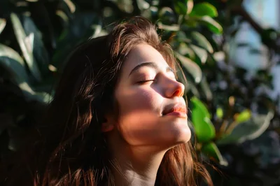 Young Woman Enjoying Warm Sunlight Outdoors