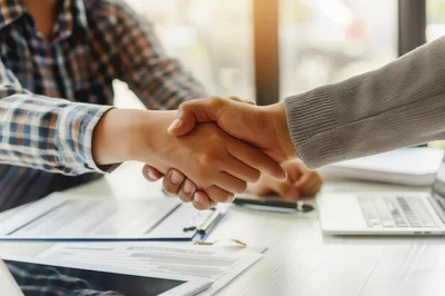 Business Professionals Shaking Hands Over Office Desk