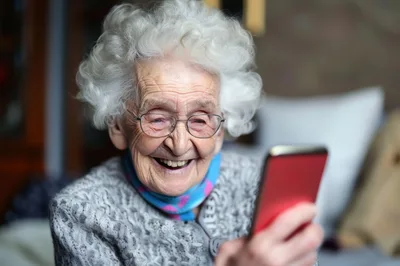 Elderly Woman Laughing While Using A Smartphone