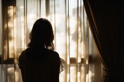 Silhouette Of A Woman Standing By A Window