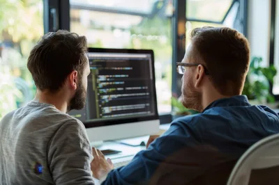 Two Software Developers Collaborating On Code At Office